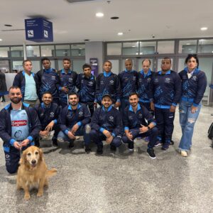 Atletas e comissão técnica e cão guia "Clark" uniformizados num aeroporto, para uma viagem em competição.